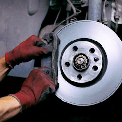 Image emphasizing worker using the proper gloves while working on brakes