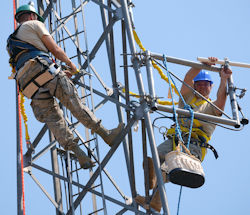 Workers safely climbing a tower using fixed ladder system.