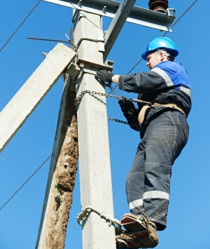 Worker high electrical pole using extra care.