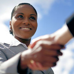 Picture of manager making eye contact, smiling and shaking hands with employee.