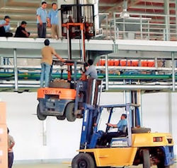 Workers performing unsafe hoisting using two forklifts