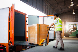 Workers placing dockboard or plate on loading dock