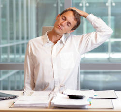 man stretching his neck at a desk