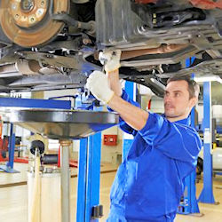 Auto technician working on oil pan plug