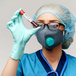 healthcare professional wearing PPE inspecting a vial of blood