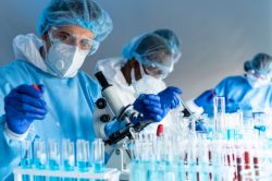 lab employees wearing full body ppe inspecting samples with microscopes