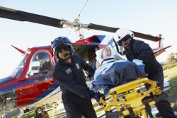 paramedics in flight gear unloading a patient from a helicopter