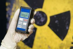 gloved hand holding a geiger counter checking the level of radiation