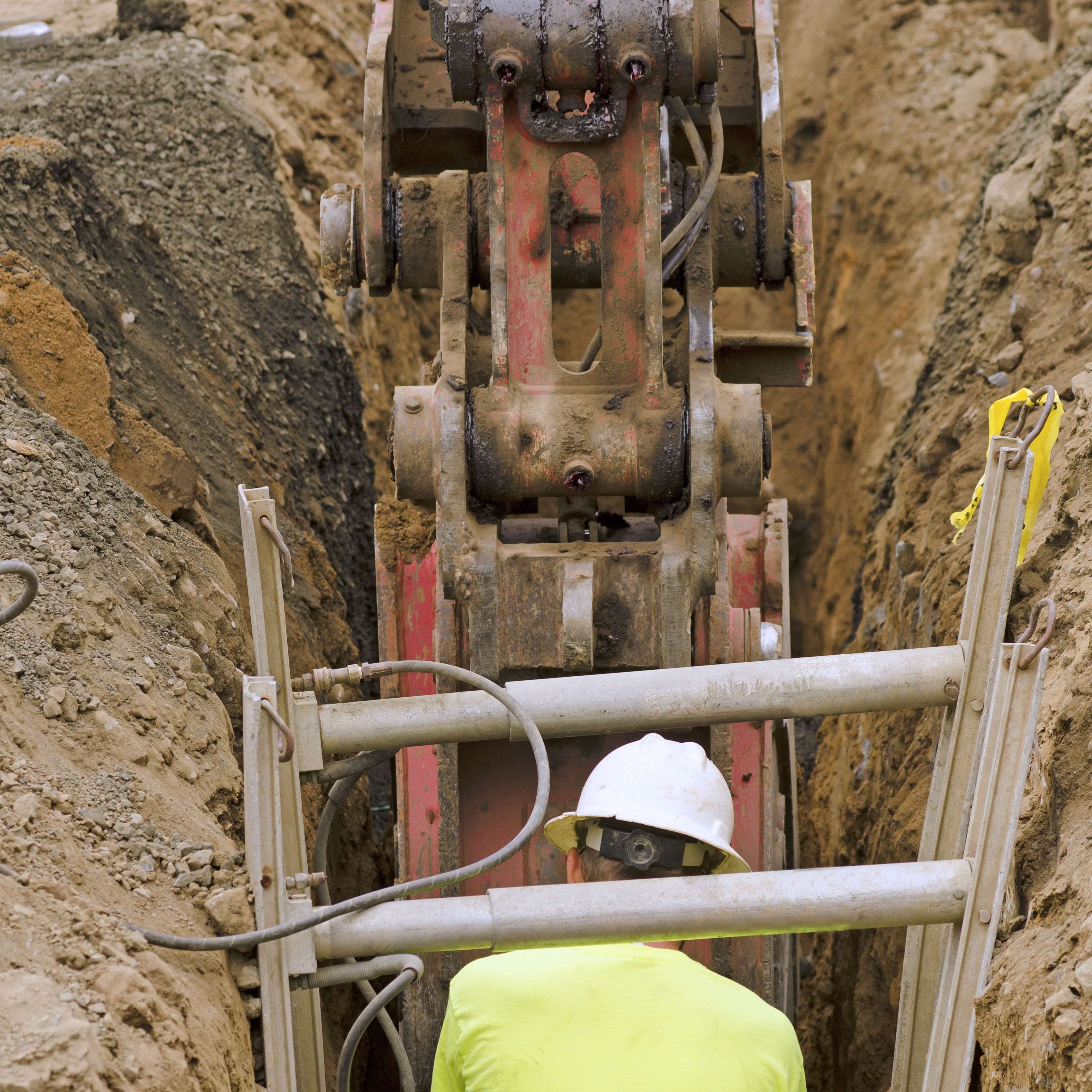 Worker in trench with mobile equipment