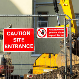 Fenced off construction site with sign showing Caution