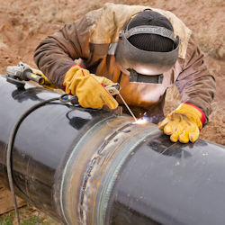 Worker outdoors welding on large pipe