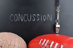 the word concussion written on a blackboard with a whistle and pieces of athletic equipment