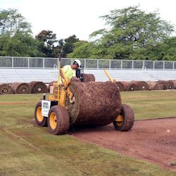 Worker laying sod on an athletic field.