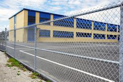 School building and blacktop with a fence in front of it.