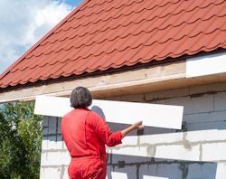 Worker doeing fascias repair on building