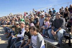 Crowd sitting on outdoor bleachers.