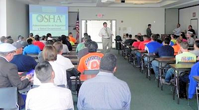 GHS Training with a room full of people sitting at desks and a trainer at the front of the room.