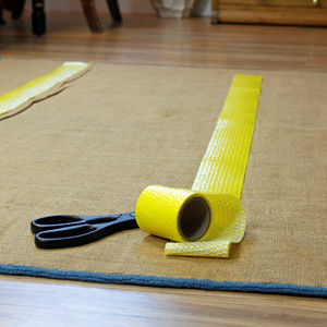 A roll of yellow anti-skid tape on the floor with scissors.