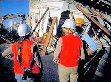 Three employees all with hard hats and two with vests looking at an accident scene.