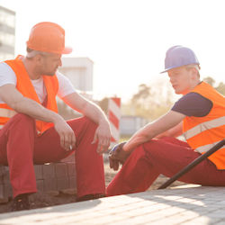 Two workers in helments and vests taking a break in the heat.