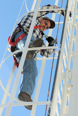 employee using a fixed ladder safety system with a cage