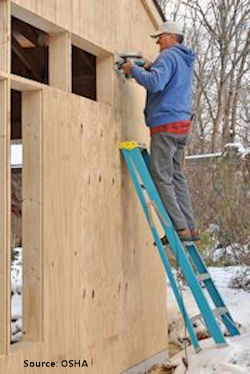 Worker unsafely standing on a ladder at a construction site