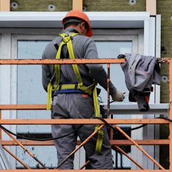 Worker on scaffold wearing a fall protection harness.