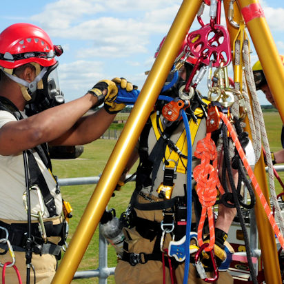 Confined space team members attaching harnesses and retrieval lines to hoist.