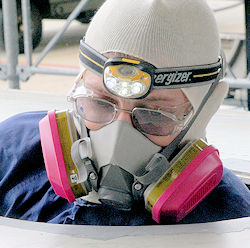 Confined space entrant wearing a respirator and entering the confined space.