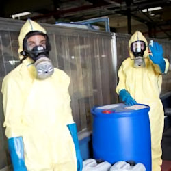 Two employees receiving PPE training with a sealed blue barrel between them