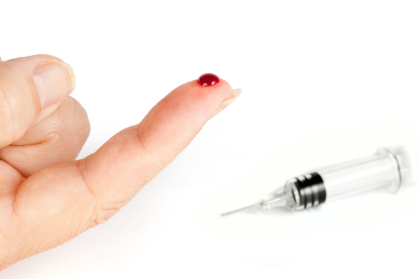 Finger on hand with a drop of blood caused by a needlestick