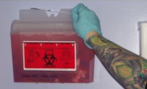 tattoo artist placing a needle in a sharps container