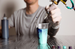 Body artist cleaning tattooing needle.