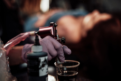 Body artist sterilizing tattoo gun and needle.