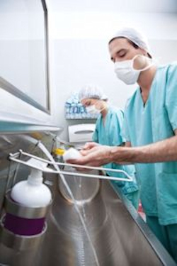 Dentist washing hands at a sink.