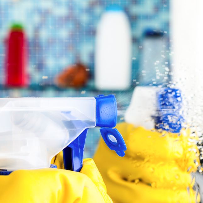 gloved hands using spray cleaner spraying towards themselves