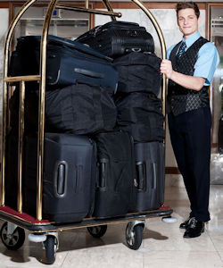 Hotel worker pushing luggage cart filled with luggage