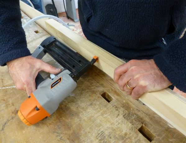 Worker using nail gun but the nail point is pointed towards his body.