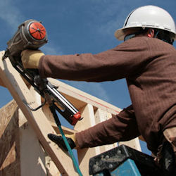 Worker on ladder using nail gun for construction work