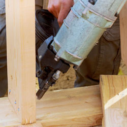 Worker toe-nailing on construction worksite