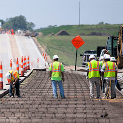 Workers preparing a road to have cement laid down on the road.