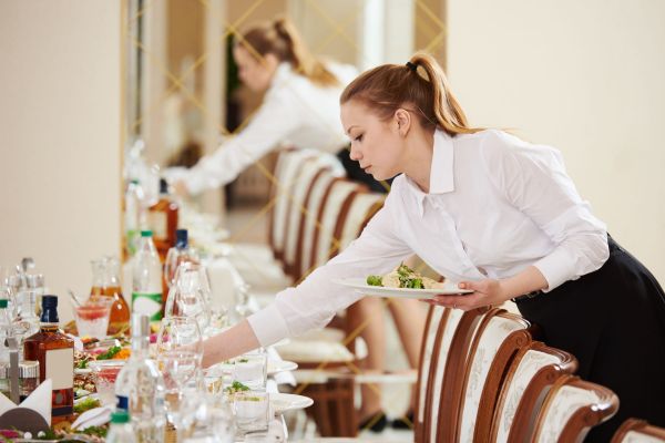 Server awkwardly reaching across a table.