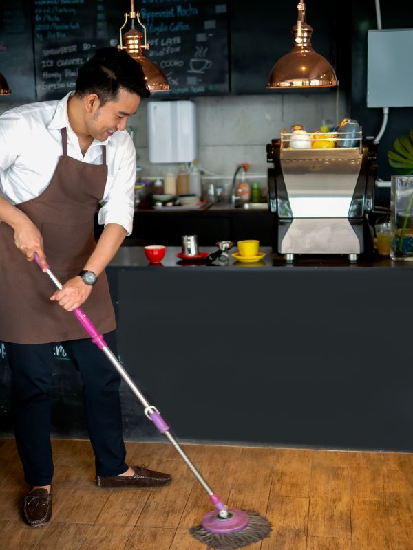 Employee mopping the floor in a cafe.