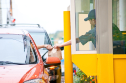 Worker handing food to a customer in a drive thru.