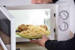 Person placing food in a microwave.