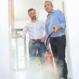 two workers using a fire extinguisher in a hallway