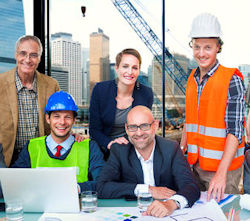 Employees in an office working together in front of a laptop.