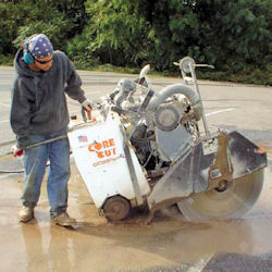 Worker cutting into cement.