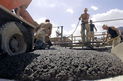 Workers at a construction site laying a cement foundation.