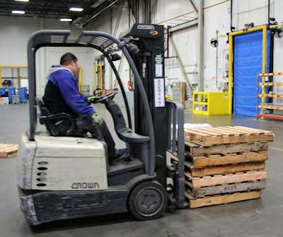 operator driving an electric forklift approaching a load